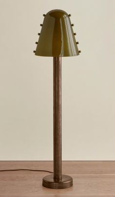 a lamp that is sitting on top of a wooden table with a white wall in the background