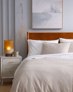 a bed with white sheets and pillows in a bedroom