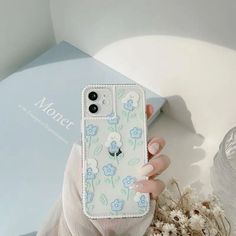 a woman is holding up her phone case with flowers on the front and back cover