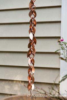 a wind chime hanging from the side of a house in front of a flower pot