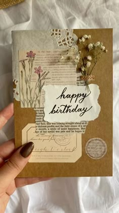 a hand holding a piece of paper with the words happy birthday on it and flowers