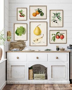 a kitchen with white cabinets and pictures on the wall