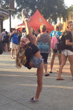 a girl doing a handstand on the street in front of a group of people