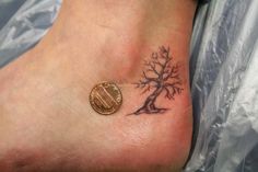 a small tattoo on the foot of a person with a coin in front of it