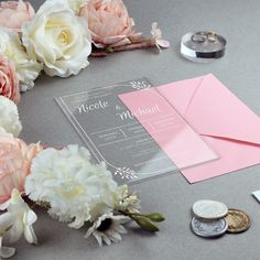 the wedding stationery is laid out on the table with pink and white flowers next to it