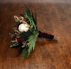 a bridal bouquet with white flowers and greenery sits on a wooden table top