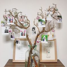 a vase filled with branches sitting on top of a wooden table next to pictures and frames