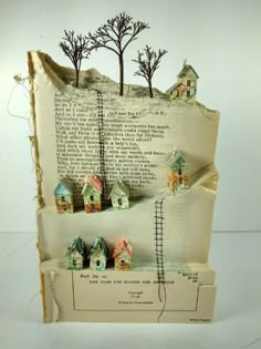 an altered book with houses and trees on it's pages, as if they were made out of old books