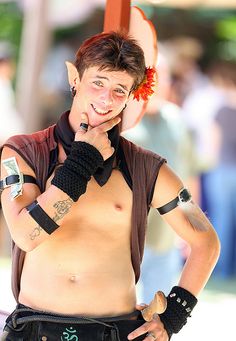 a shirtless man with tattoos on his chest and arm, holding a cell phone to his ear