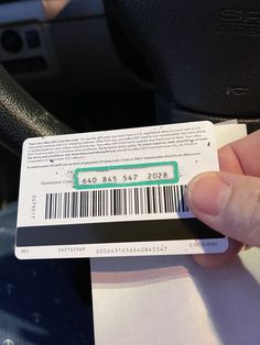 a hand holding a barcode on top of a car steering wheel