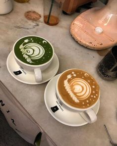 two coffee cups with designs on them sitting on a table next to some other items