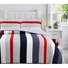 a white bed with red, blue and black striped bedspread