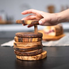 a stack of wooden coasters being held by a person's hand on top of a table