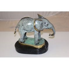 an elephant figurine sitting on top of a black and green base with gold accents