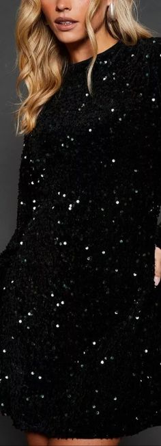 a woman wearing a black dress with silver sequins on the sleeves and shoulders