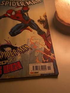 a spider - man comic sitting on top of a table next to a candle