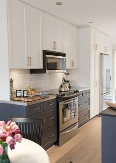 a kitchen with white cabinets and stainless steel stove top oven in the middle of it