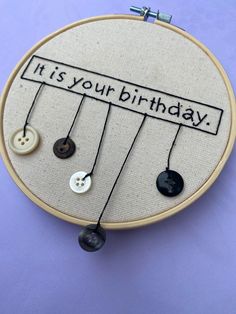 a hand embroidered birthday card with buttons attached to the back of an embroidery hoop that says, it's your birthday