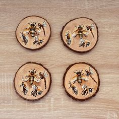 four wooden coasters with bees painted on them