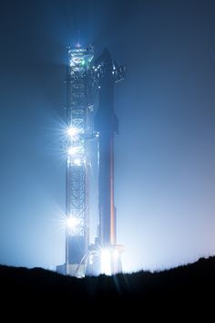 the space shuttle is lit up at night with bright lights on it's side