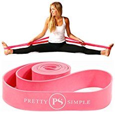 a woman sitting on top of a pink yoga mat and holding a pair of red straps