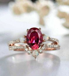 a pink ring with white stones on the side and an oval shaped stone in the middle