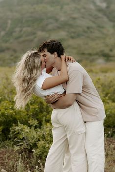 a man and woman kissing in the middle of a field