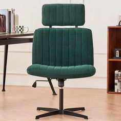 a green office chair sitting on top of a hard wood floor next to a book shelf