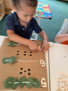 two children are playing with letters and numbers made out of brown paper on the table