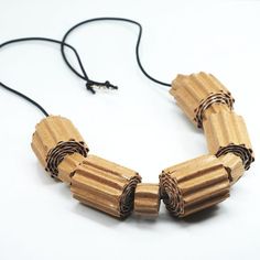 a necklace made out of wooden sticks on a white surface with a black cord attached to it