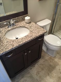 a white toilet sitting next to a sink in a bathroom under a mirror and shower