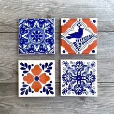 three square tiles with blue and orange designs on them, sitting on a wooden surface