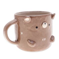 a ceramic mug with faces and eyes on it's side, sitting in front of a white background