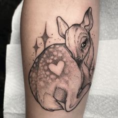 a black and white tattoo of a deer holding a heart