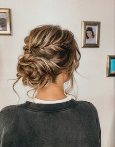 a woman with her hair in a low bun is looking at pictures on the wall