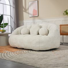 a white couch sitting on top of a rug in a living room next to a window