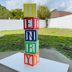 a colorful block sculpture sitting on top of a cement slab in front of a yard