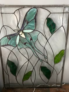 a stained glass panel with green leaves and a blue butterfly on it's wings