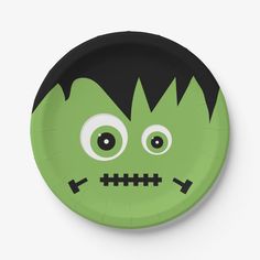 a paper plate with a green monster face on it's side and black eyes