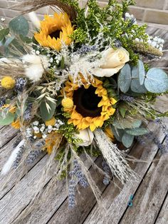 a bridal bouquet with sunflowers, feathers and greenery on a wooden table