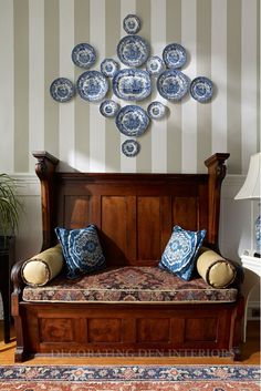 a wooden daybed with blue and white plates on the wall above it in a living room