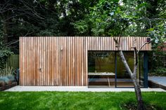 a small wooden structure in the middle of a yard with trees and grass around it