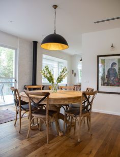 a dining room table with chairs and a painting on the wall