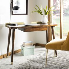 a room with a desk, chair and lamp on it in front of a window