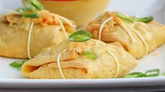 some food on a white plate with sauce and green garnishes in the background