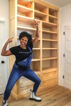 a woman standing in front of a bookshelf with her arms up and smiling