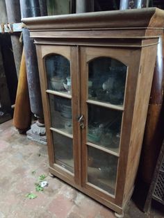 a wooden cabinet with glass doors on the top and bottom shelves in front of it