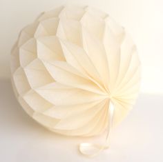 a white paper ball sitting on top of a table next to a string attached to it