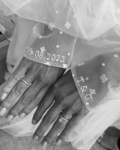 black and white photograph of two brides hands with wedding rings on their fingernails