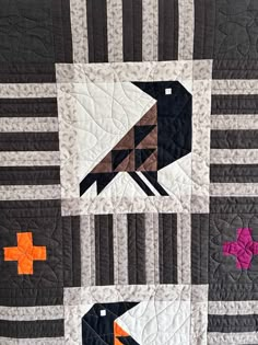 a black bird sitting on top of a quilt